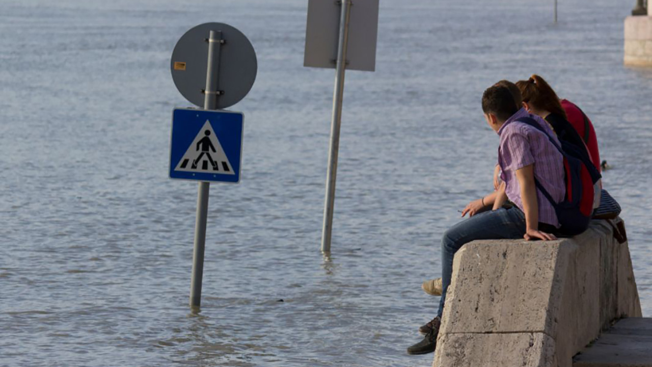 People sitting near flooded street signs